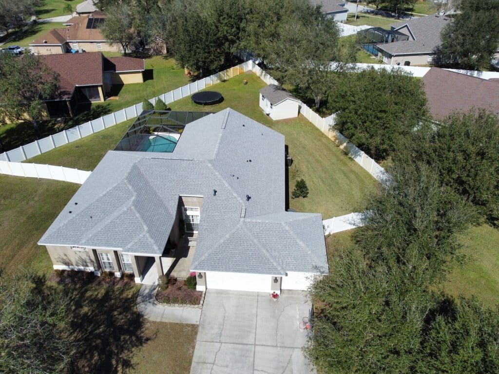 Aerial view of a home with a gray roof and pool
