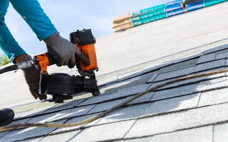 Roofer using a nail gun to install shingles